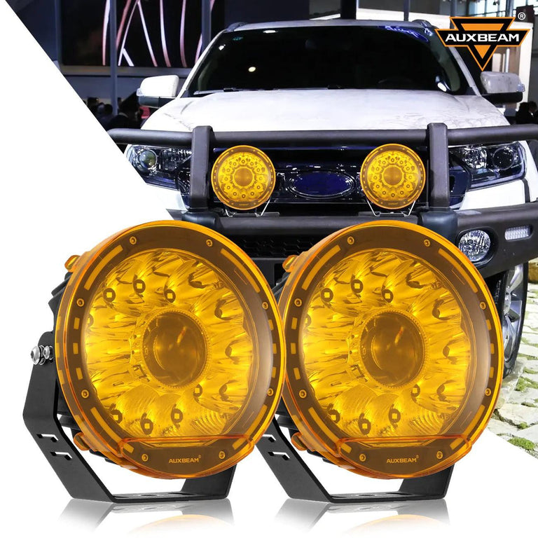 Pair of Auxbeam 7-inch 360-PRO round LED driving lights with amber covers, mounted on a truck bumper