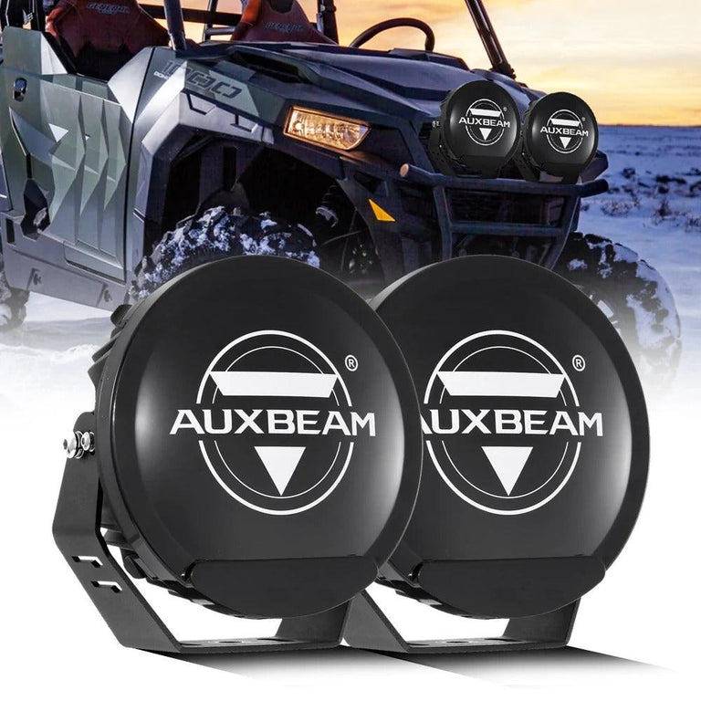 Pair of black Auxbeam 7-inch light covers with logo, with a UTV fitted with the same covers behind them